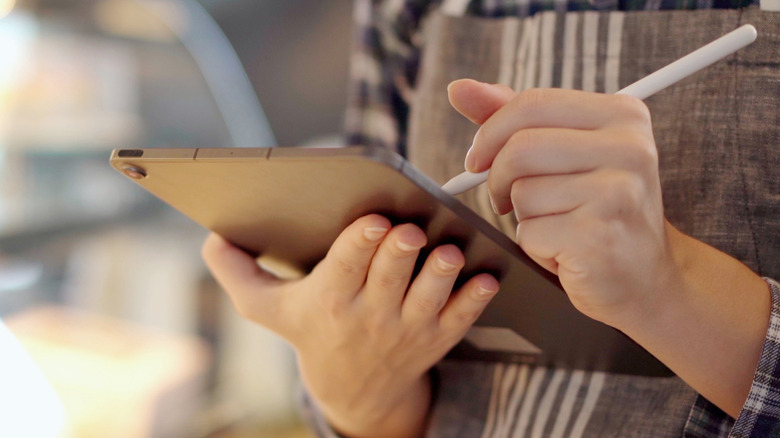 closeup of hands checking off list on tablet