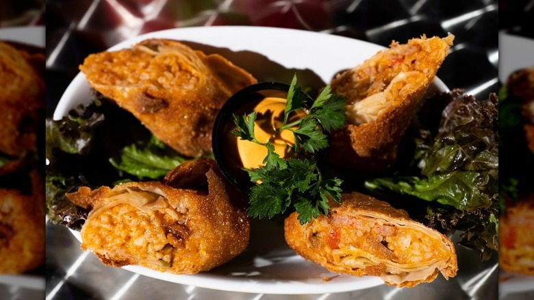 egg rolls on plate with sauce and garnish in center