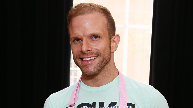 Zac Young smiling while wearing a blue shirt and an apron