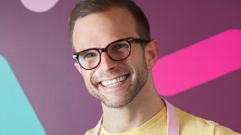 Zac Young smiling while wearing a yellow shirt and an apron