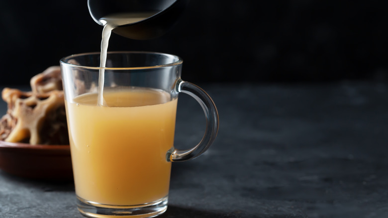 .Beef broth in a clear cup in a ladle