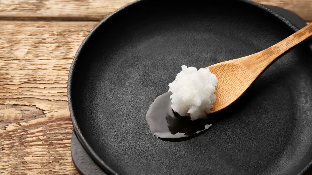 spoonful of coconut oil melting in a frying pan