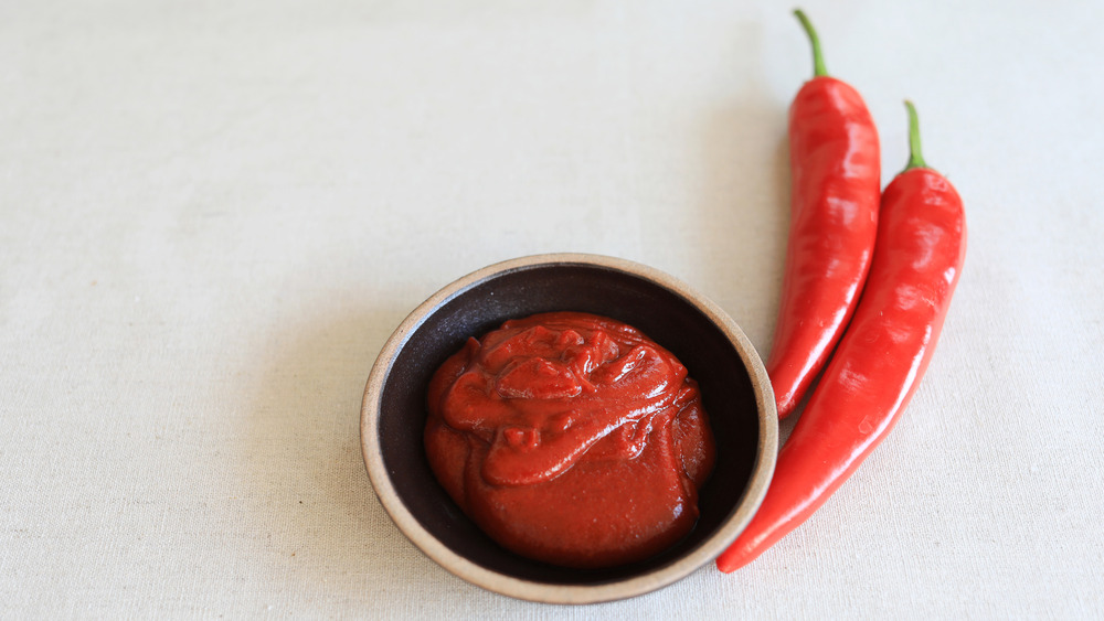 bowl of gochujang beside peppers