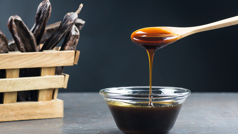 glass bowl and wooden spoon with molasses dripping