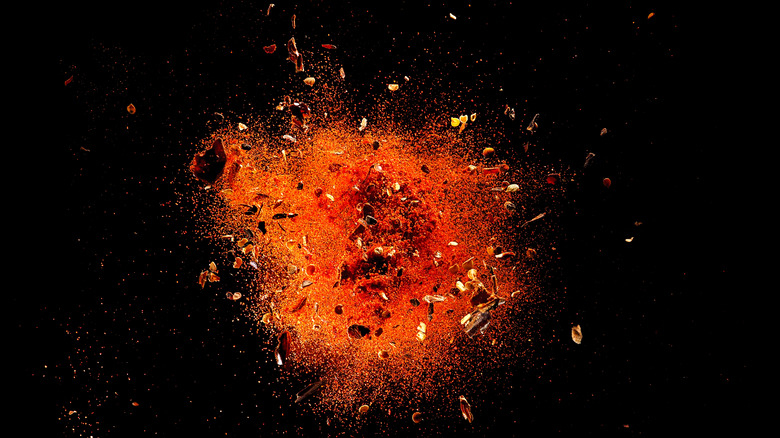 red cayenne powder and flakes on black background