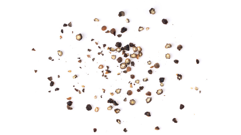 crushed black peppercorns on white background