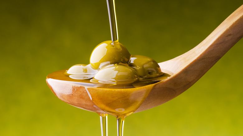 Olive oil being poured over a spoon 