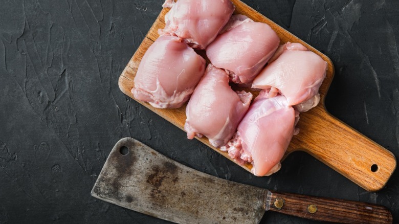 raw chicken thighs and cleaver