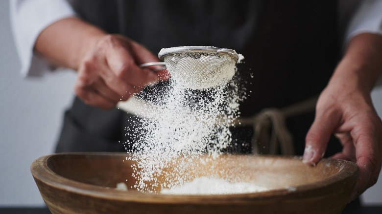 Flour being sifted over a bowl. 