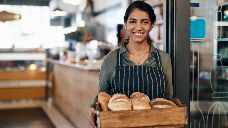 baker holding tray of bread in bakery