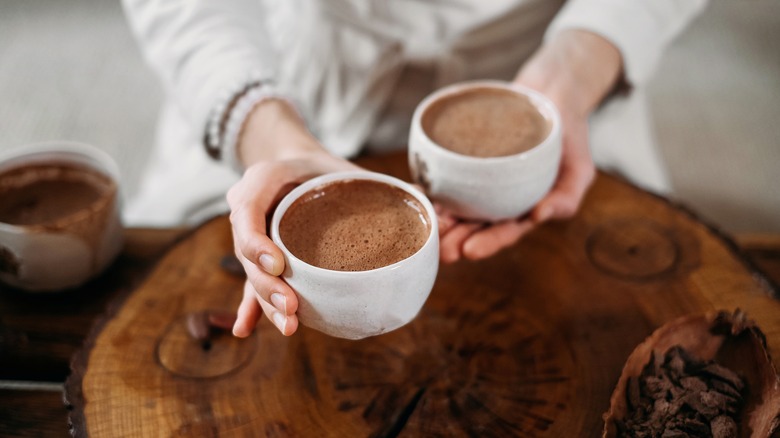 woman holding two cacao drinks