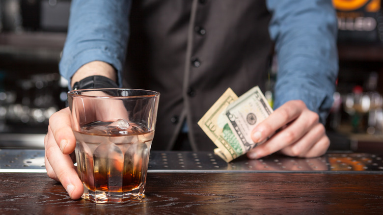 bartender with cash and drink