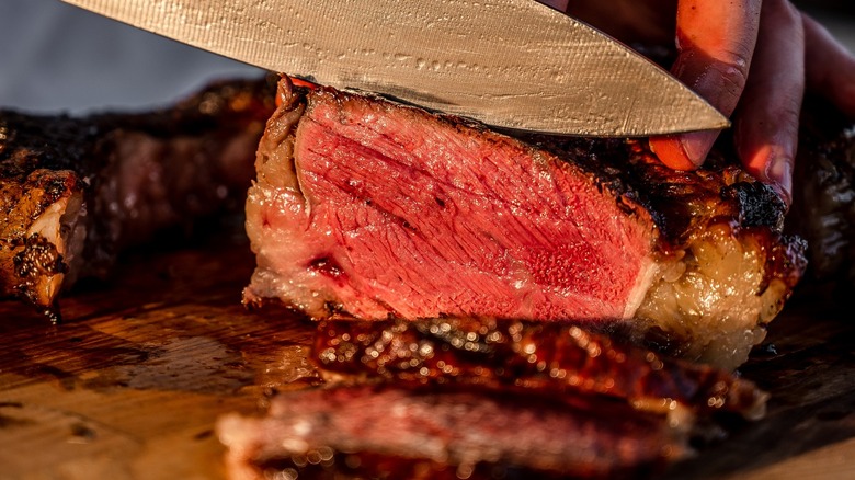 Knife slicing into rare steak