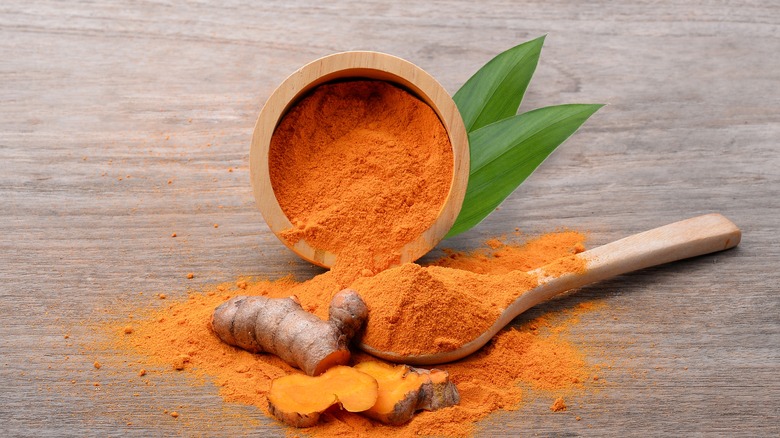 Turmeric in a wooden bowl with a wooden spoon