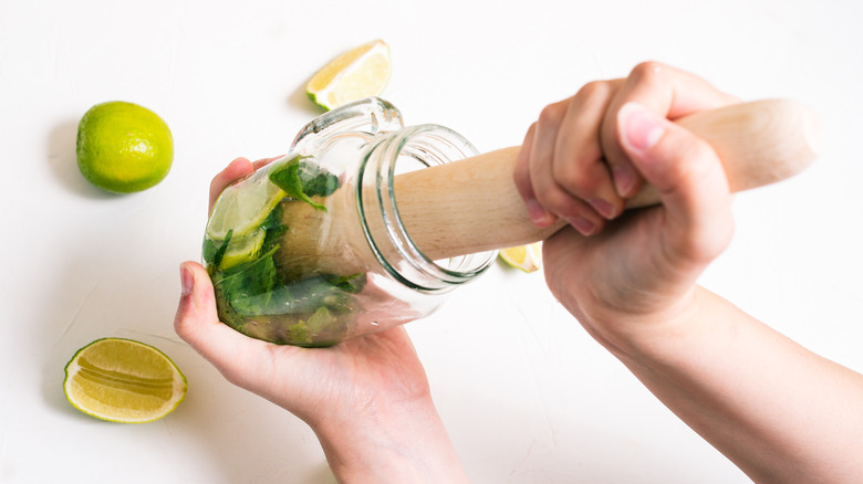 Muddling limes in a jar