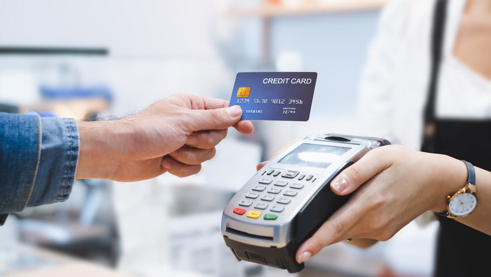 hand holding credit card above credit card machine