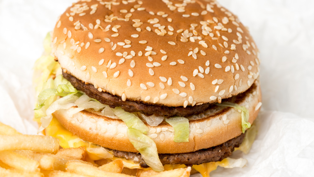 fast food burger on white paper with french fries