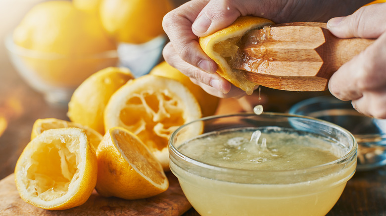 Hands using juicer on lemon halves. 