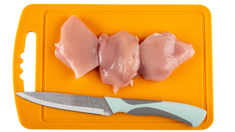 Raw chicken on plastic cutting board