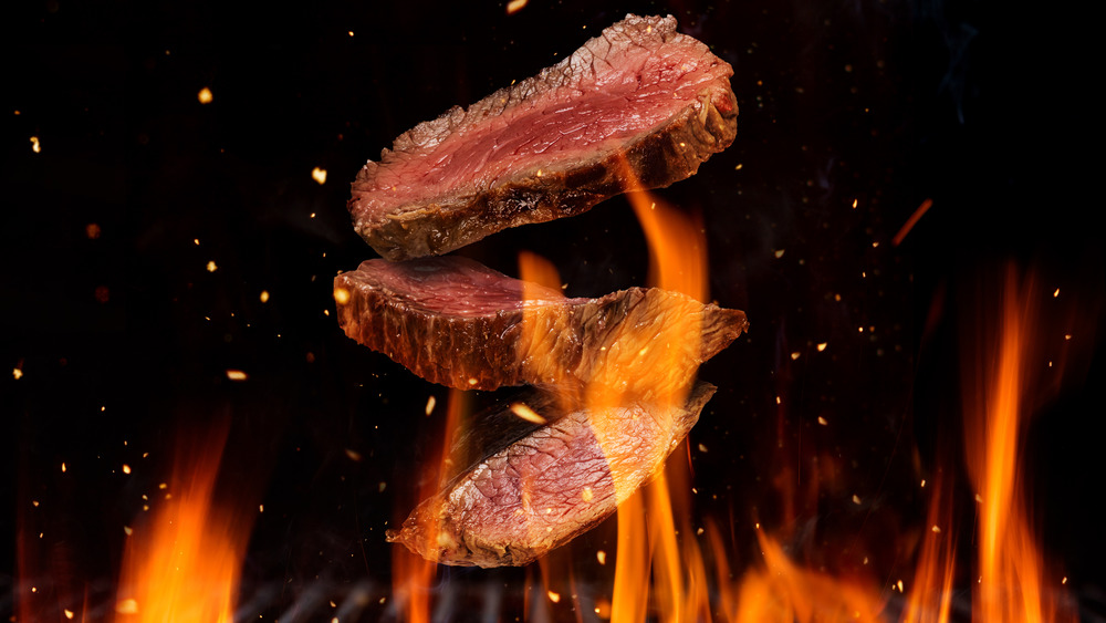 Steaks cooking over open flame
