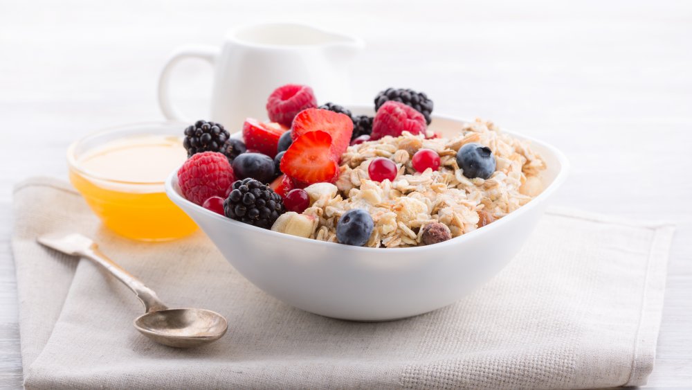 bowl of oatmeal topped with berries next to honey for topping