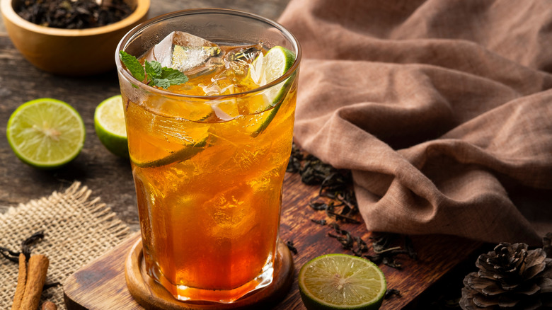 Glass of iced tea with mint and limes on a dark rustic background