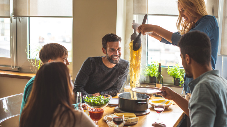 people happily eating pasta meal