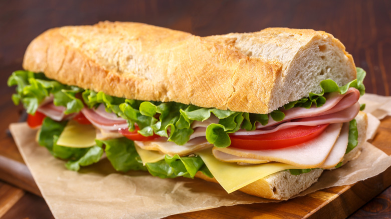 Subway sandwich on paper atop wooden board