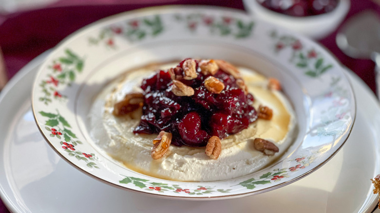 cranberry-cheese spread in a holly-patterned bowl on a white plate