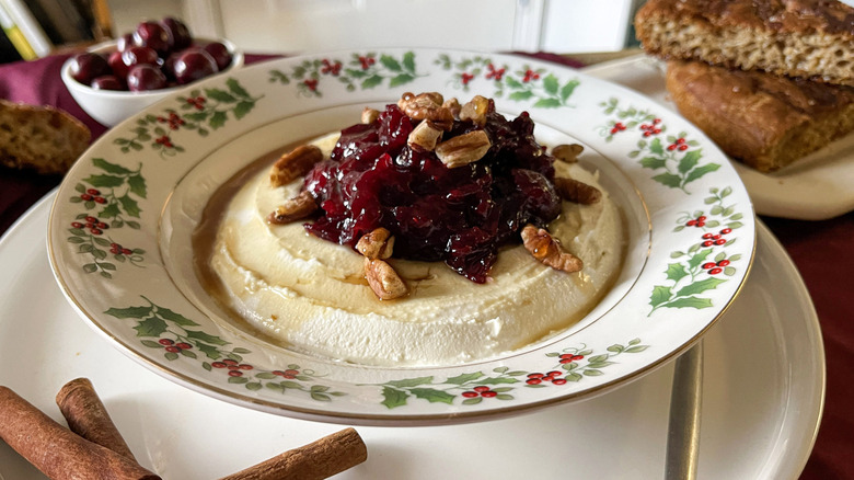 cranberry-cheese spread in a holly-patterned bowl on a white plate