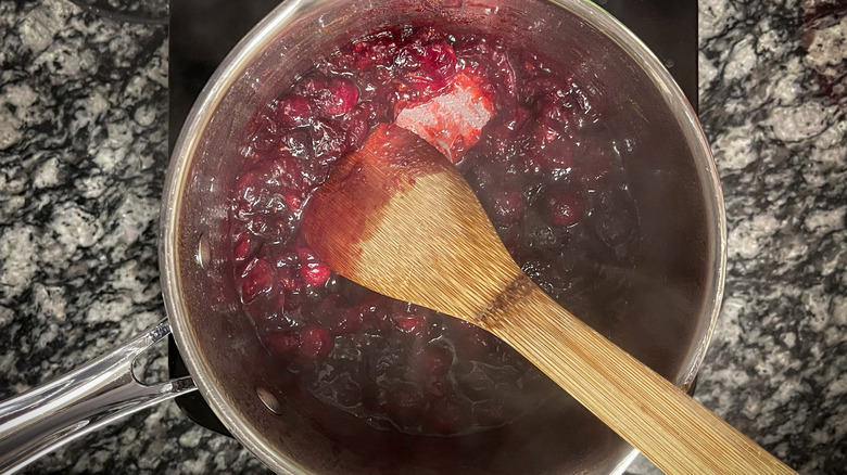 cranberry sauce in a metal pot with a wooden spatula