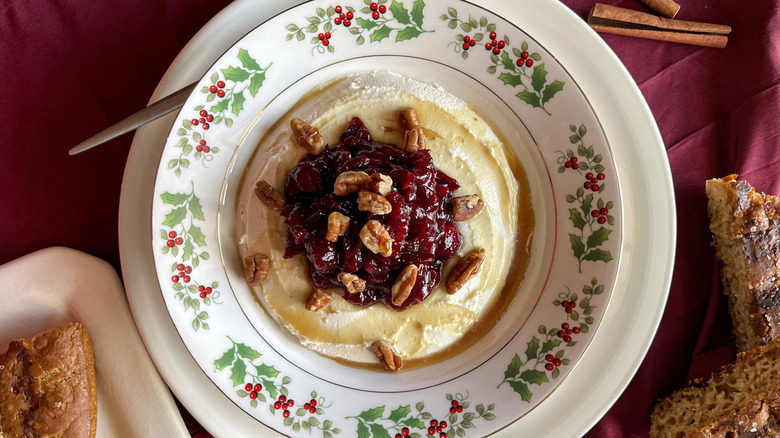 cranberry-cheese spread in a holly-patterned bowl on a burgundy napkin