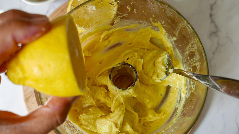 squeezing lemon into aioli