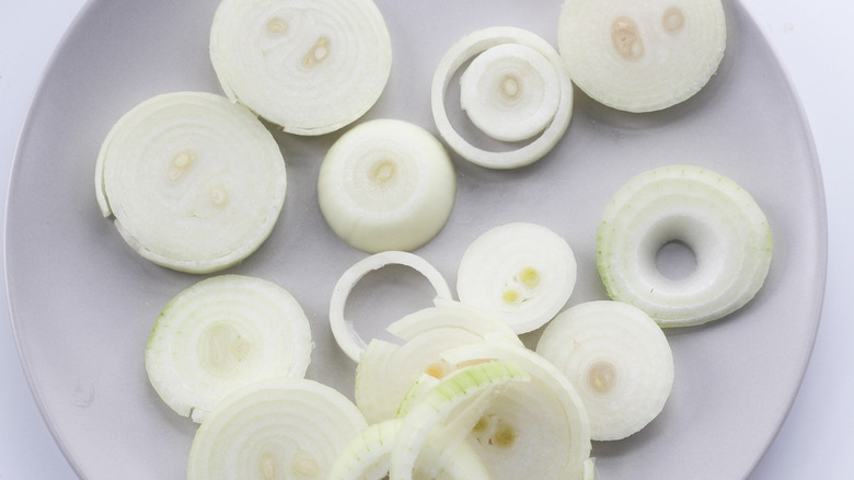 Peeled and sliced onions on a plate.