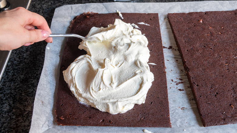 spreading vanilla ice cream onto the brownie layer