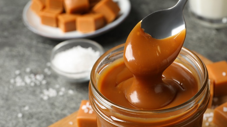 Spoon dripping caramel dip over glass jar