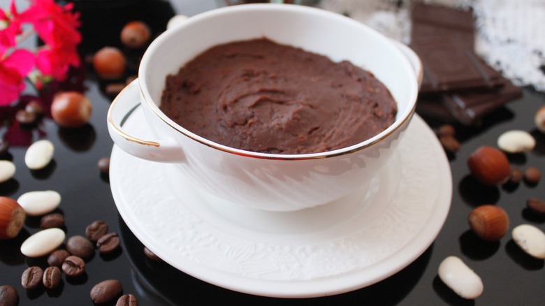 Chocolate hummus in white mug with nuts and coffee beans