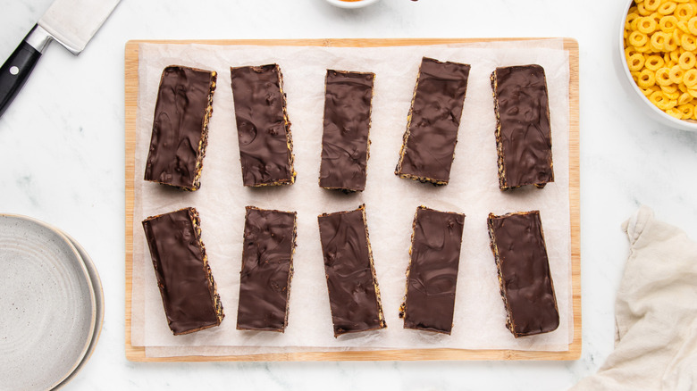 Chocolate-topped cereal bars on parchment-lined cutting board