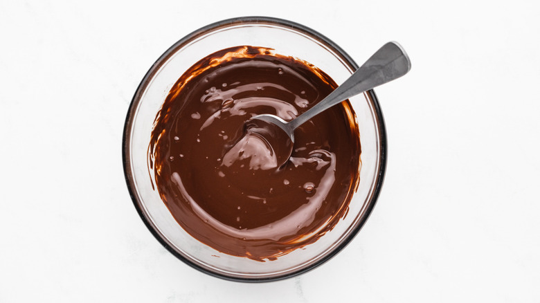 Melted dark chocolate in glass bowl with spoon