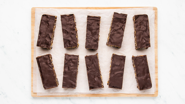 Chocolate-topped cereal bar slices on parchment-lined cutting board