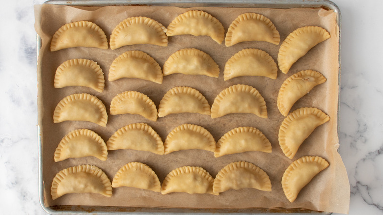 filled empanadas on baking sheet