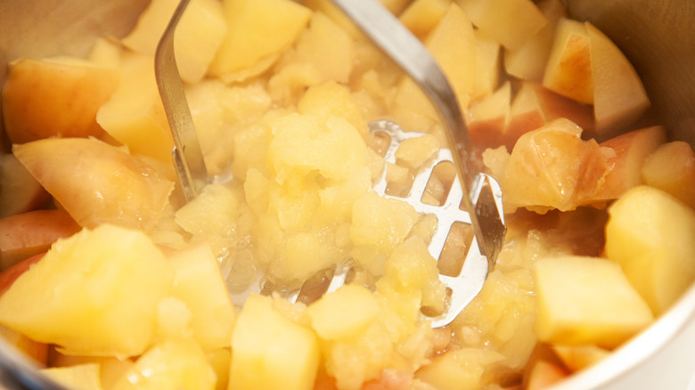 mashing cooked apples in bowl