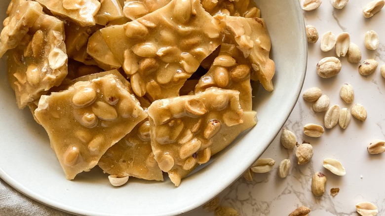 Homemade peanut brittle pictured on a background of scattered peanuts