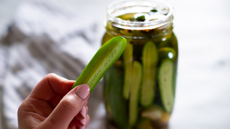 Hand with pickle and jar