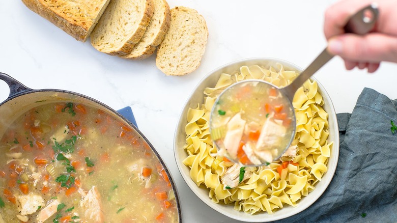 Ladle turkey soup over noodles