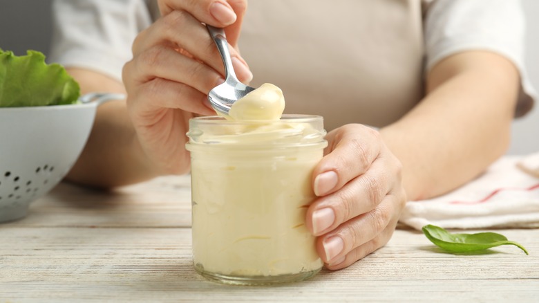 person holding jar of aioli