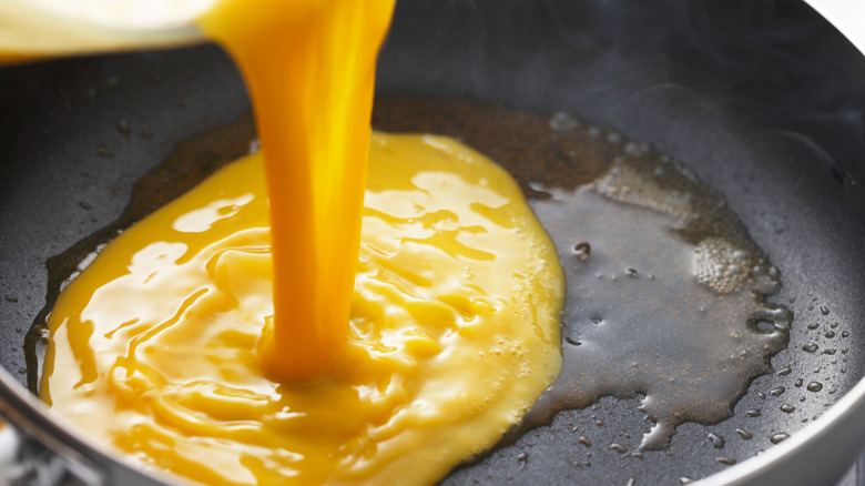 pouring egg mixture into pan for omelet