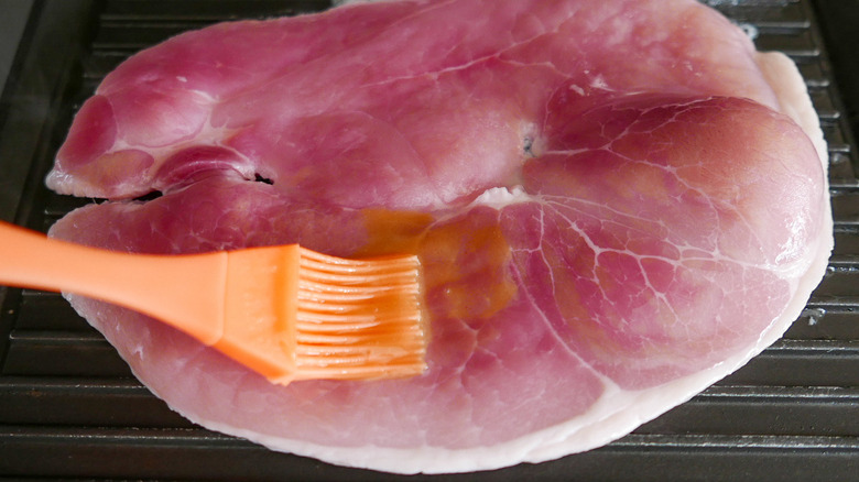 brushing ham steak with glaze