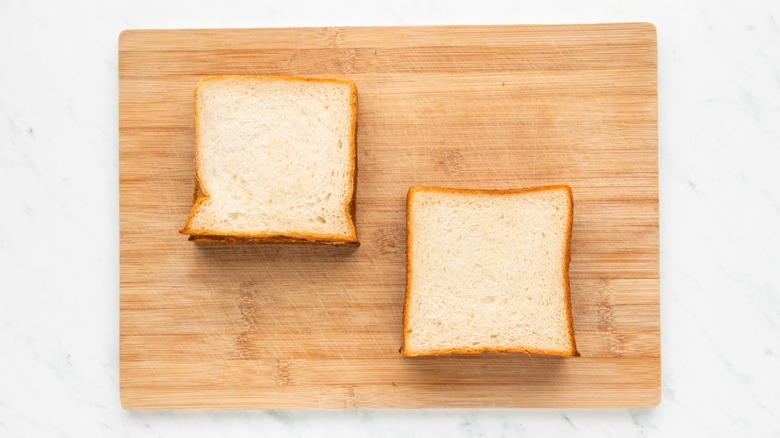 Two milk bread sandwiches on wooden cutting board