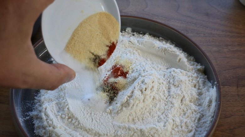 pouring spices onto plate of flour